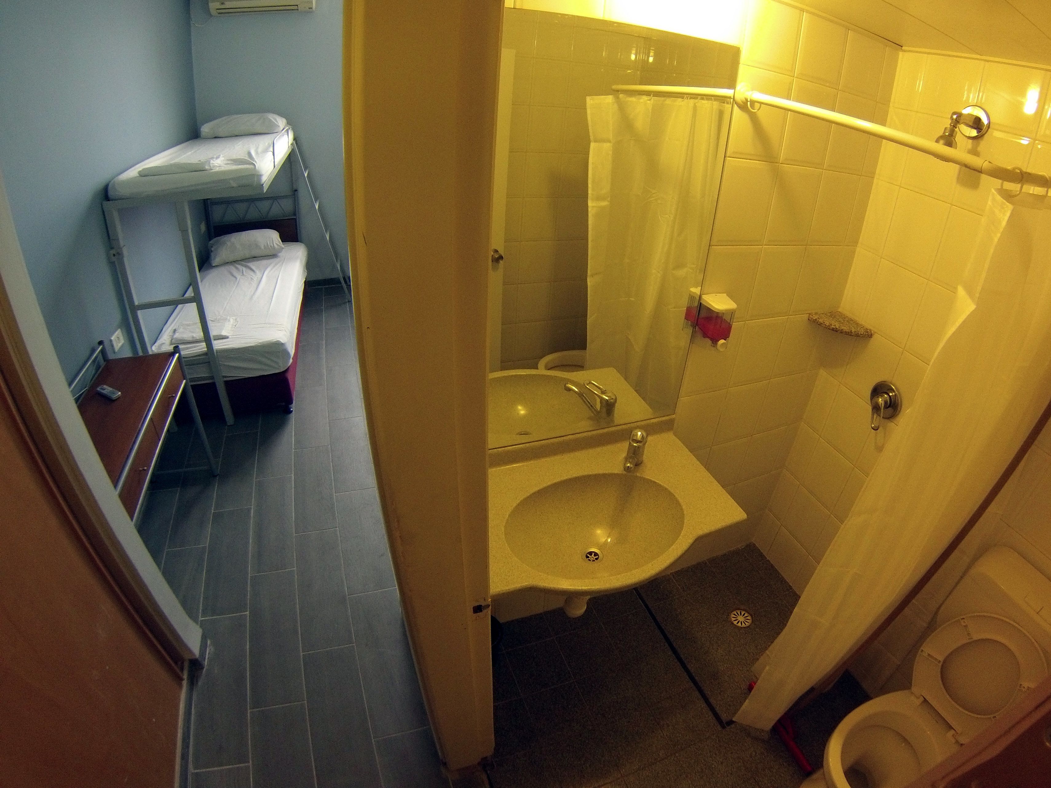 Una habitación pequeña y funcional con literas, lavabo e inodoro.