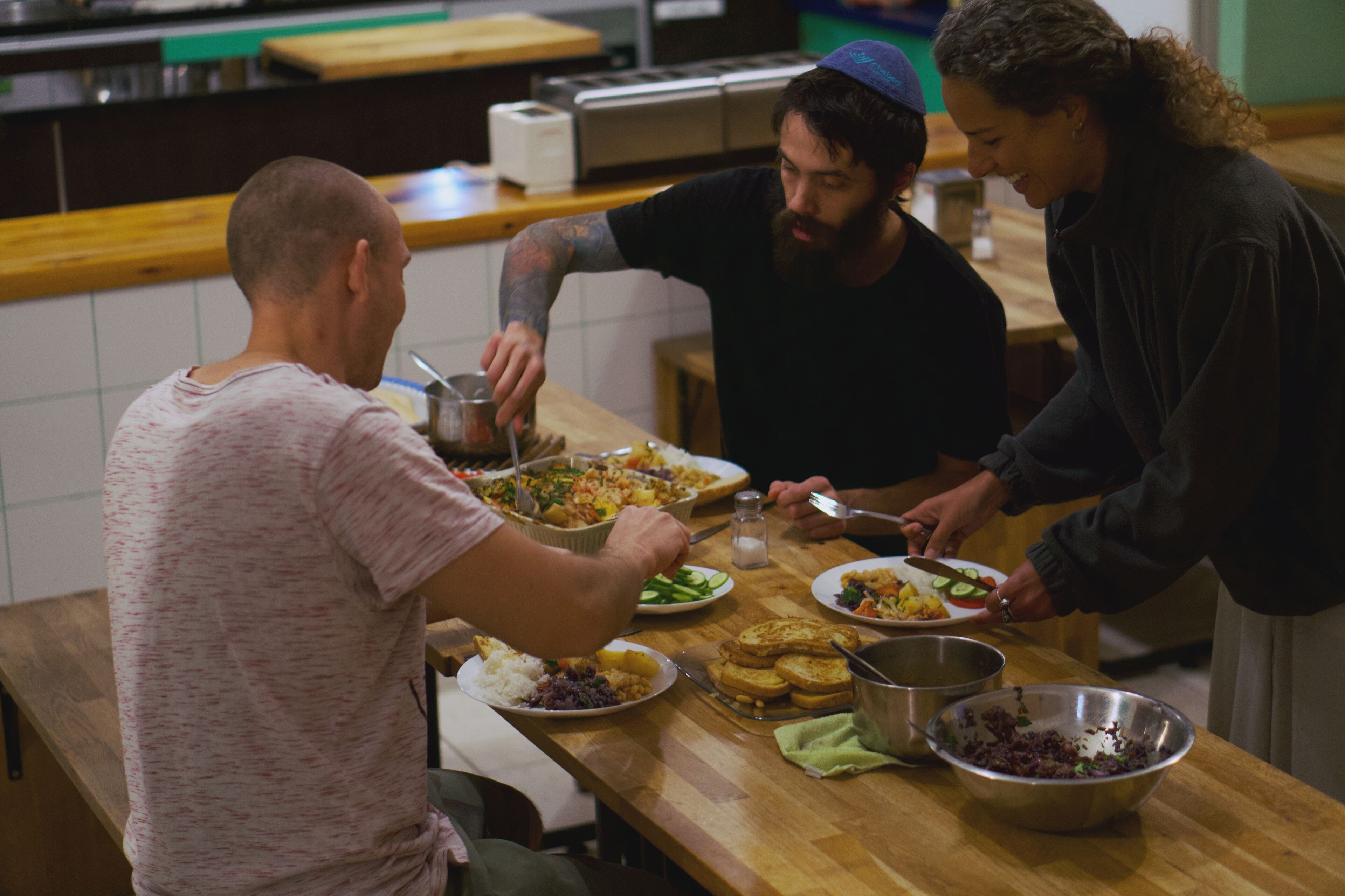 Un grupo de personas cenando en una mesa de madera con varios platos.