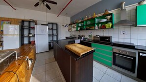 A modern kitchen with a wooden island, built-in appliances, and green cabinetry. - Tiberias Hostel (Tiberias)