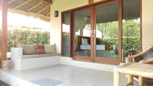 Una habitación con sofá, una mesita y ventana con vista a follaje.