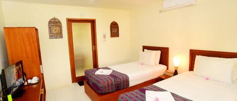 A hotel room with two beds, a desk with a computer, a mirror, and a ceiling fan.