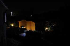 A house with a yellow facade, surrounded by greenery, and illuminated by multiple lights. - Luce Stellata (Podenzana)