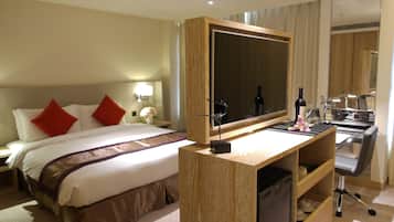 A hotel room with a bed, a desk with a mirror, a small sink, and a compact dishwasher.