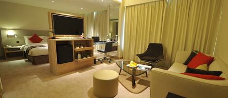 Una habitación de hotel con cama, escritorio, sofá, mesa de centro y televisor.