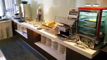 A buffet setup with a coffee machine, a toaster, and a glass display case with food items.