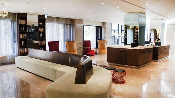 A modern living room with a sofa, chairs, a coffee table, and a dining area with a counter and chairs. - Kaohsiung International Plaza (Kaohsiung)