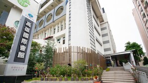 A modern building with a prominent entrance, a vertical wooden fence, and a staircase leading to the entrance. - Kaohsiung International Plaza (Kaohsiung)