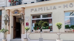 A hotel facade with the name "FAMILIA-HOTEL" above the entrance. There are potted plants on the windowsill and a sign with the letter "H" on the wall. - Familia Hotel (Paris)