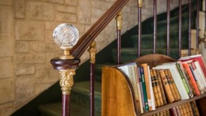 A staircase with a wooden handrail and a bookcase filled with books. - Familia Hotel (Paris)