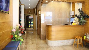 Un área de recepción con un mostrador de madera, un banco y una decoración floral.
