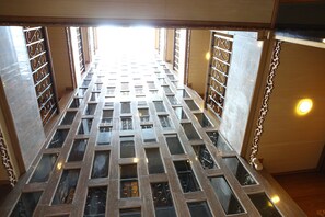 A high-ceilinged, open-plan lobby with a grid of windows and metal railings. - Tanee Place (Bangkok)