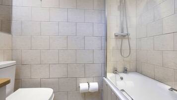 A bathroom with a toilet, a shower area, and a bathtub.