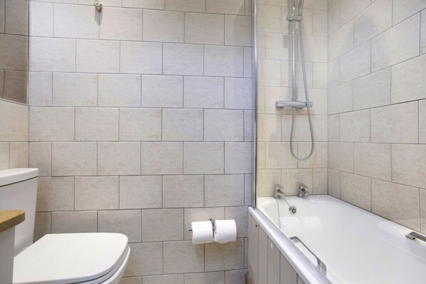 A bathroom with a toilet, a shower area, and a bathtub.