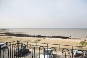 A beach with a promenade and parked cars.