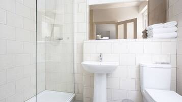 A modern bathroom with a glass shower enclosure, a pedestal sink, and a toilet.