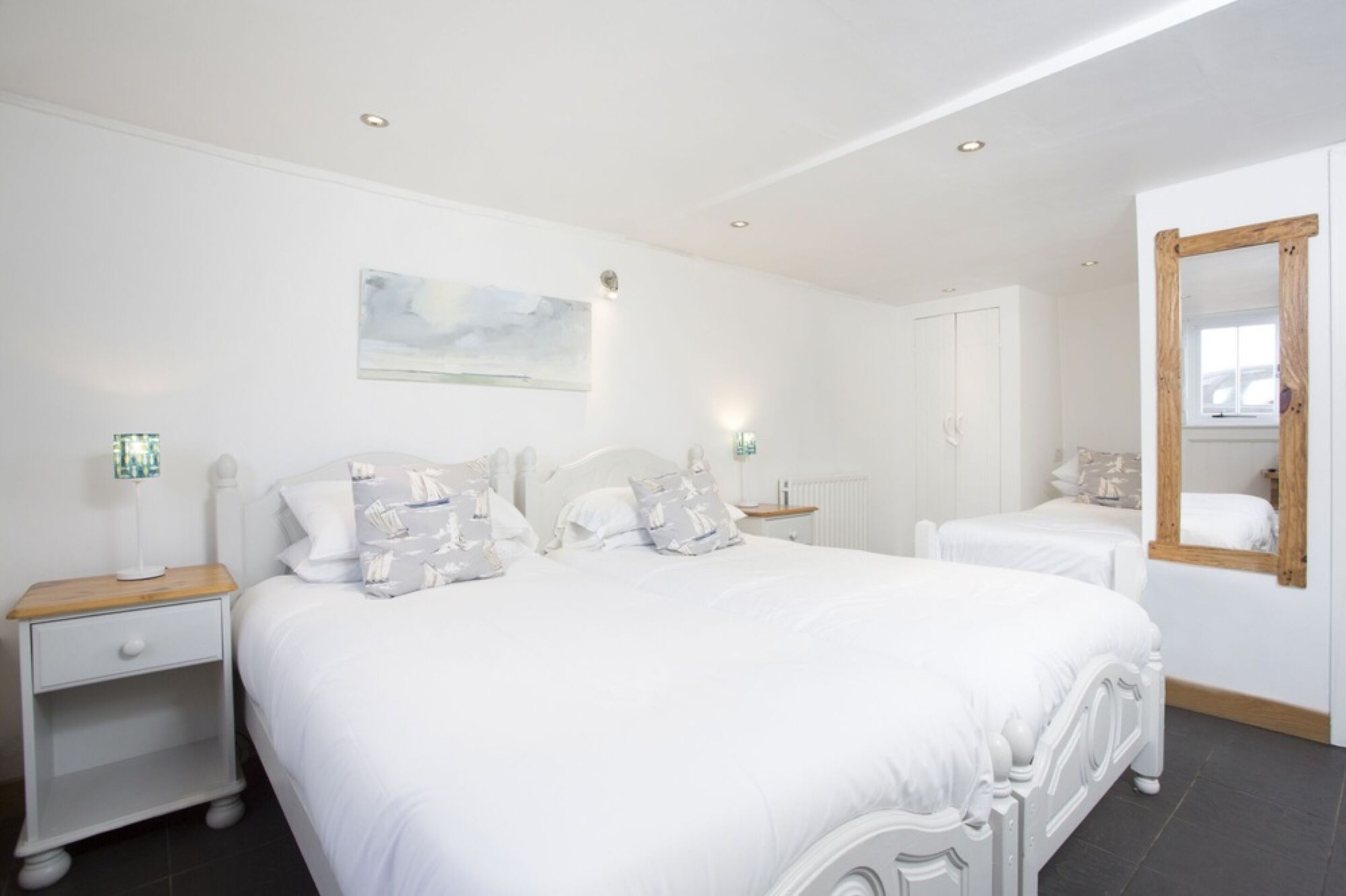 Een slaapkamer met een groot bed, twee nachtkastjes, een spiegel en een schilderij aan de muur.