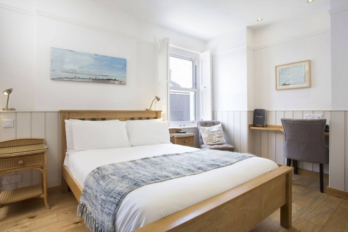 Un dormitorio con una cama de madera, una mesita de noche, una silla y una ventana.