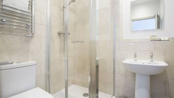 A bathroom with a glass-enclosed shower, a white sink, and a toilet.