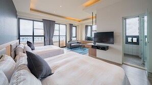 A modern hotel room with two large beds, a flat-screen TV, a seating area with a sofa and a small table, and a balcony with a view. - Florence Resort Villa (Ren'ai)
