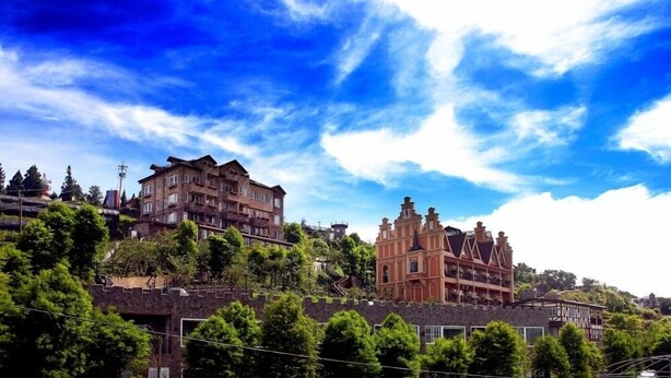 A historic building with multiple stories and a traditional architectural style, surrounded by lush greenery. - Florence Resort Villa (Ren'ai)