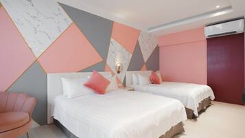 Habitación de hotel con dos camas, una silla rosa y una pared con diseño geométrico.