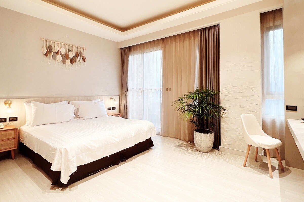Un dormitorio moderno con una cama grande, un escritorio y una planta en maceta.