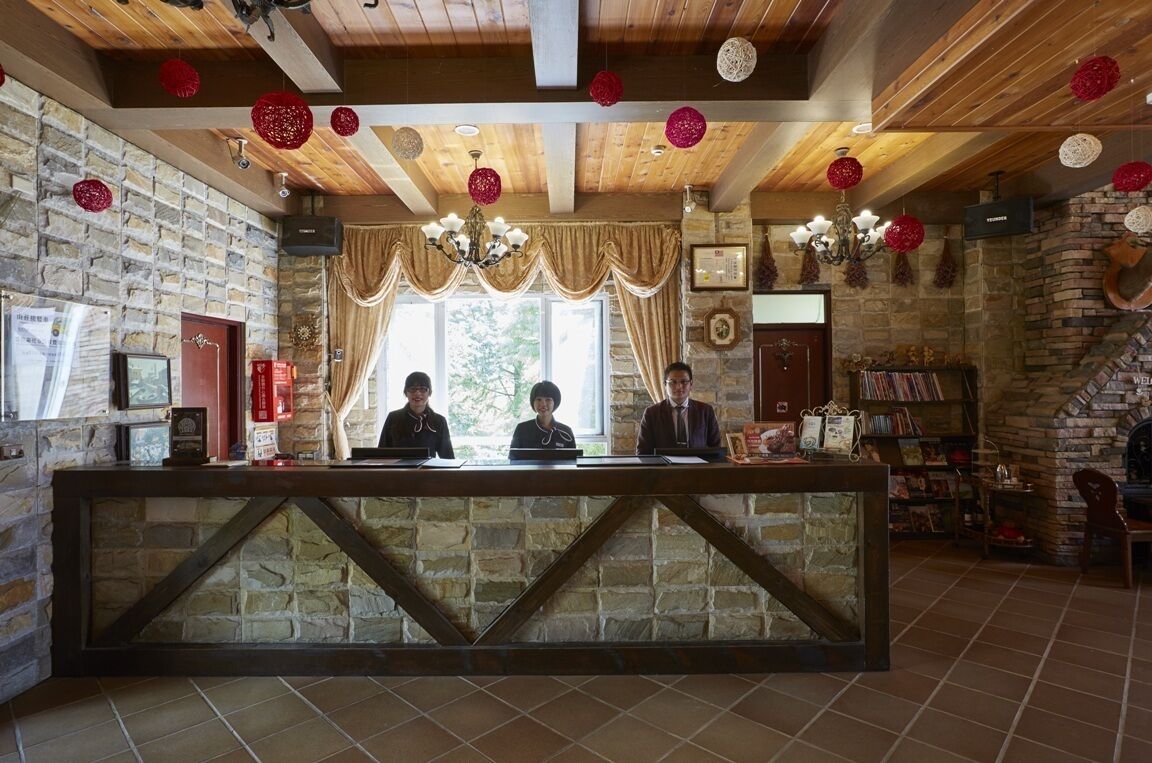 A reception area with a stone wall, wooden ceiling, and a reception desk.