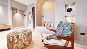 A modern interior with a wooden chair, a woven ottoman, and a bench with patterned cushions. - Florence Resort Villa (Ren'ai)