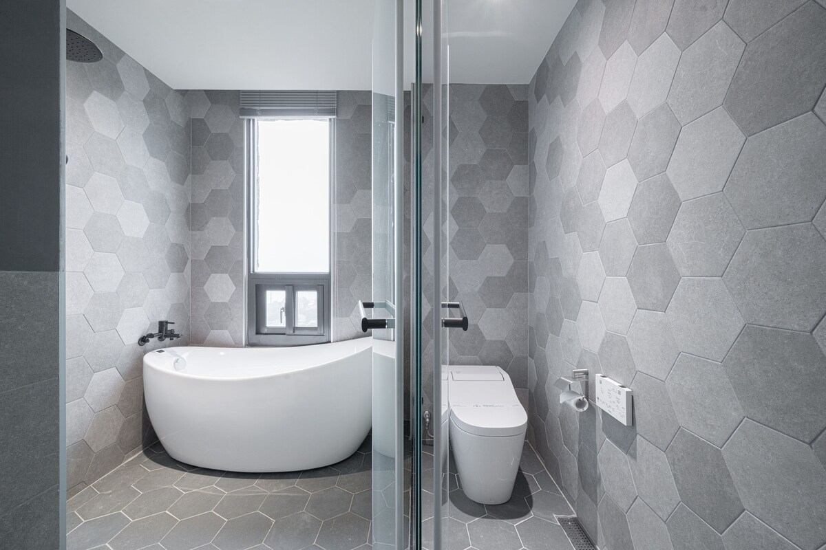 A modern bathroom with a large freestanding bathtub, a toilet, and a glass shower enclosure.