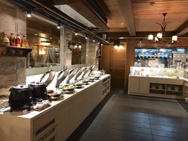 Montaje tipo bufé con varias estaciones de comida, una zona de cocina y techo de madera.