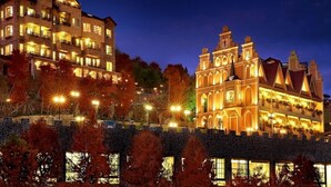 A large, multi-story building with illuminated windows and balconies, surrounded by trees. - Florence Resort Villa (Ren'ai)
