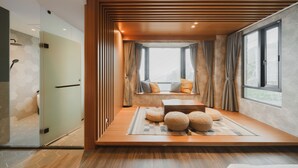 A modern room with a wooden platform, a seating area with cushions, a small table, and a view through large windows. - Florence Resort Villa (Ren'ai)