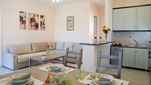 Una sala de estar moderna con sofá, mesa de comedor y zona de cocina.