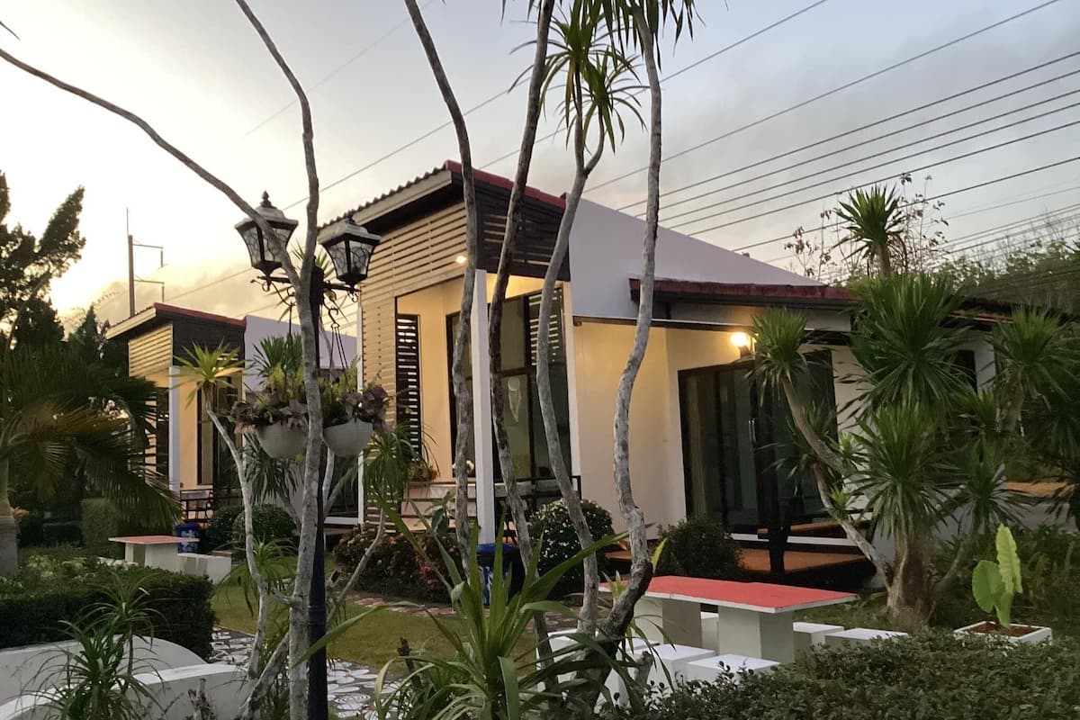 Een modern huis met een rood dak, omgeven door weelderige begroeiing en een verzorgde tuin.