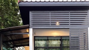 Un bâtiment moderne doté de grandes fenêtres et d’un espace extérieur aménagé avec des sièges, protégé par un auvent.
