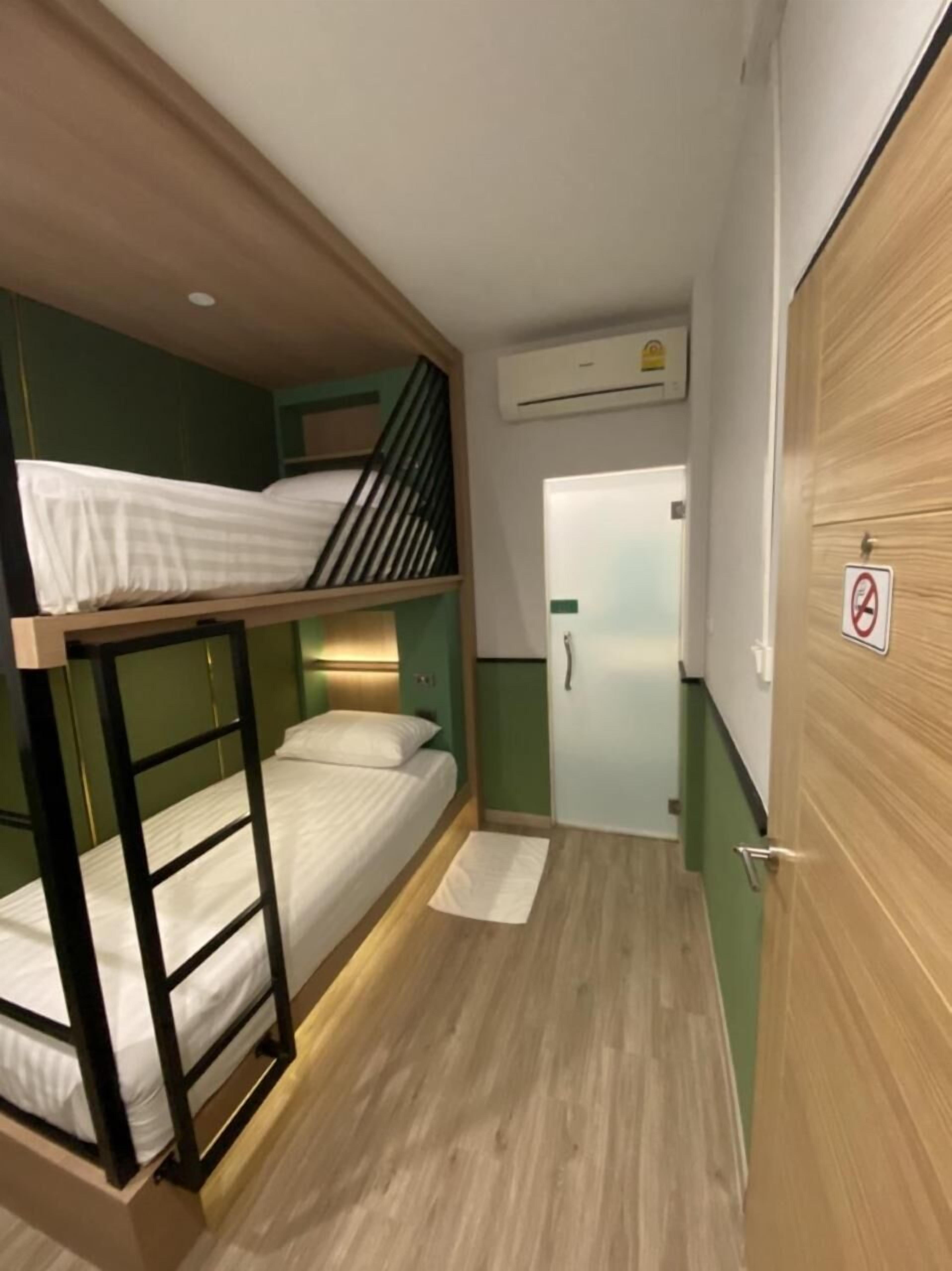 Un pasillo estrecho con literas a un lado y una puerta al otro.