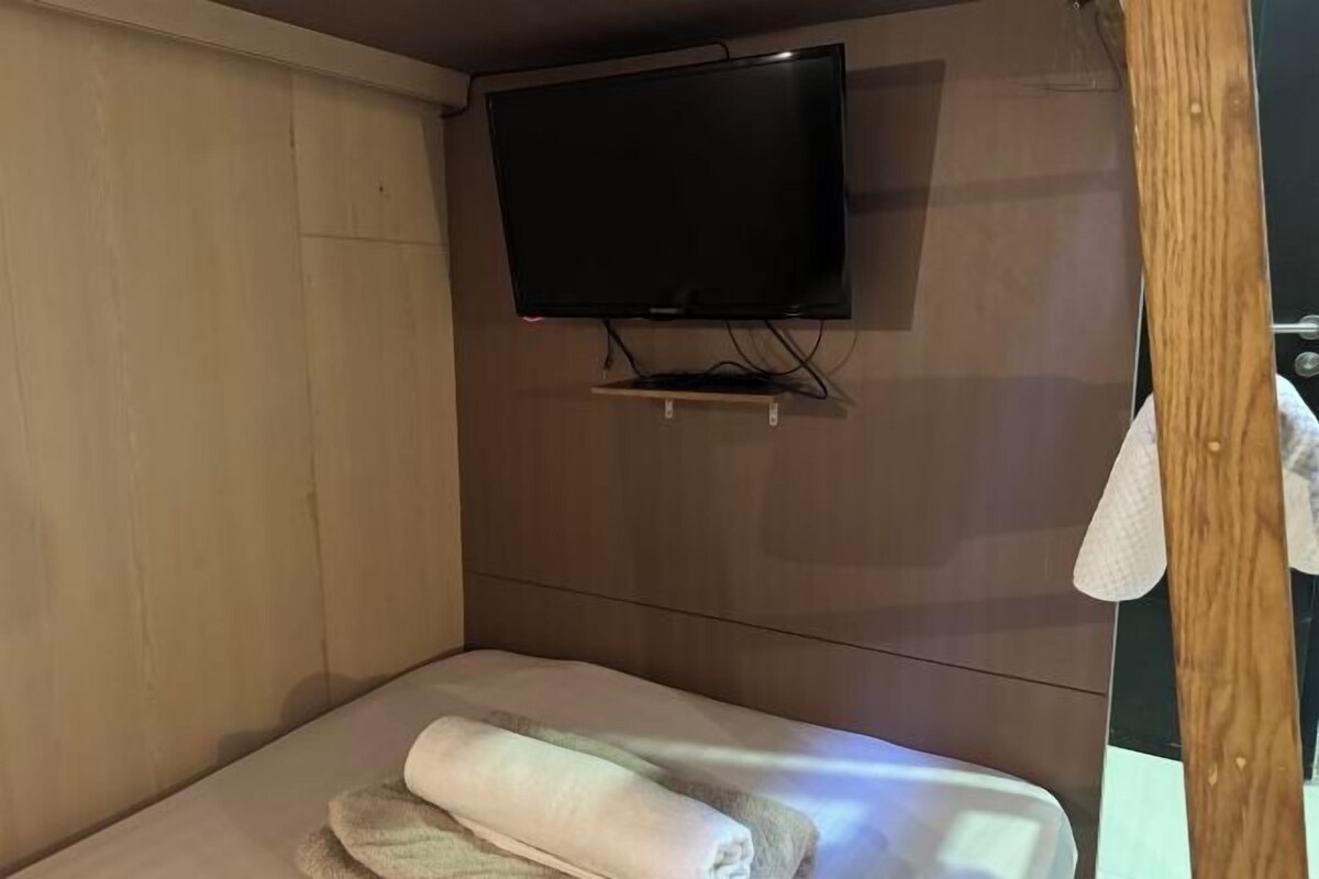 A room with a bed, a television mounted on the wall, and a wooden door.