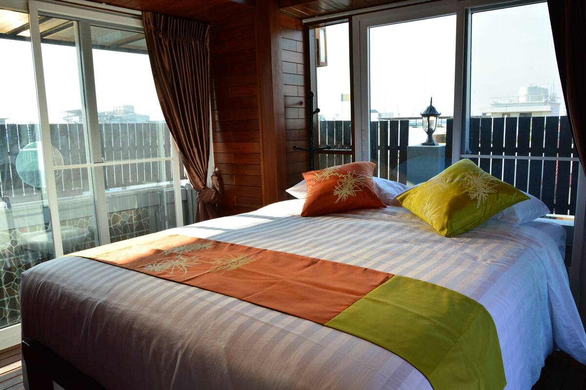 A hotel room with a large bed, a balcony with a view, and a wooden interior.