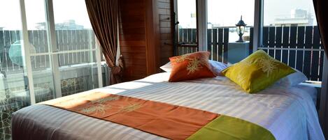 A hotel room with a large bed, a balcony with a view, and a wooden interior.