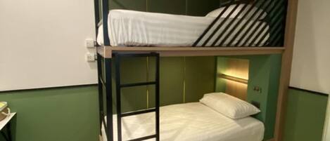 A bunk bed with a ladder, a bedside table, and a small rug.