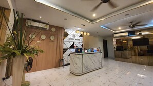 A hotel lobby with a reception desk, clocks displaying different cities, and a ceiling fan. - Adamaz House (Bangkok)