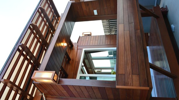 A modern wooden staircase with built-in lighting, leading to a balcony with a glass door. - Adamaz House (Bangkok)