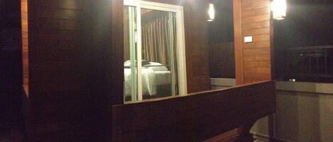 A room with a wooden bench, a bed with a white cover, and a window with curtains.