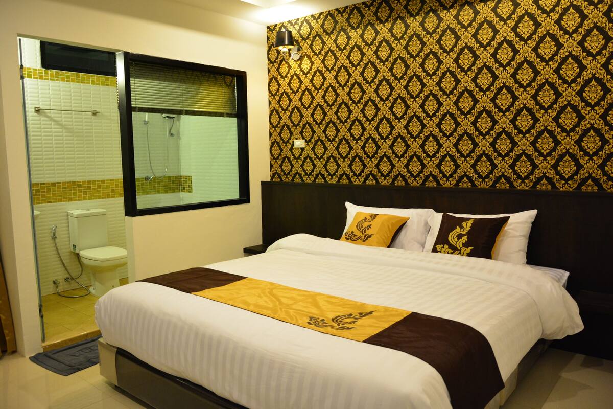 A hotel room with a bed, a bathroom, and a patterned wall.
