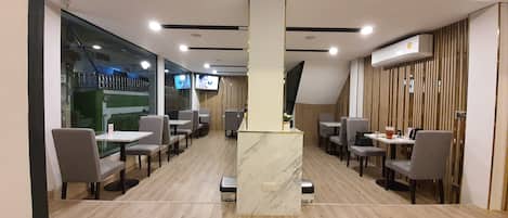 A modern restaurant with a central marble counter, multiple tables, and chairs.