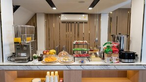 A breakfast bar with a coffee machine, fruit, pastries, and condiments. - Adamaz House (Bangkok)