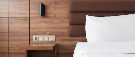 A wooden wall with a bedside table, a power outlet, and a switch.