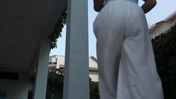 Una persona caminando hacia un edificio de fachada blanca y hiedra verde.