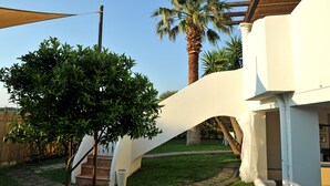 A modern house with a curved staircase, a palm tree, and a clear sky. - Il Leone di Mare (Procida)