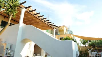 Una casa moderna con un espacio exterior cubierto, una escalera y un jardín.